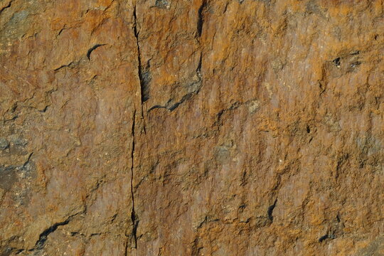 Background from a stone of igneous rock. Wallpaper made of textures of boulders of volcanic origin. Surface of granite, diabase, gabbro interspersed with spar, quartz. Sea shore. Day. Georgia.