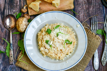 Italian creamy  cheese risotto with parmesan cheese and fresh basil on rustic background