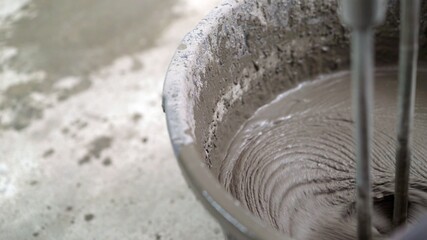 The solution in the bucket is mixed using a construction mixer. Mixing plaster solution in a bucket...