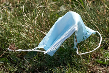 Used blue face mask on the ground in the grass. Face mask is disposed of incorrectly. Nature...