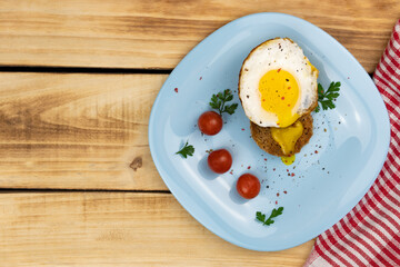 Top view of fried egg with crouton, cherry tomatoes on blue plate