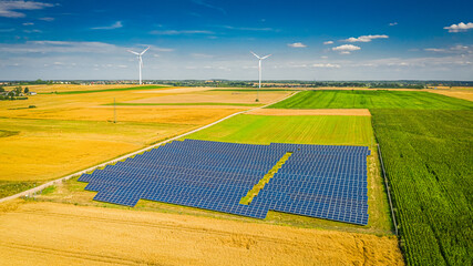 Solar panels on field with wind turbines, aerial view