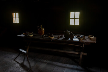 Interior of an old country farmhouse with wooden table, clay bowls and dishes