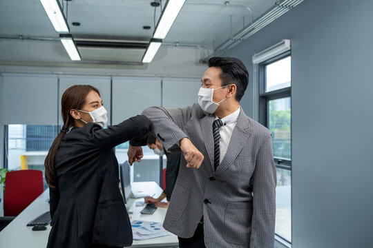 Businessman and businesswoman with medical mask in office after covid-19 quarantine and lockdown,Greetings in Covid-19 time.