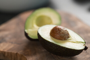 Ripe avocado sliced in halves on olive wood board closeup