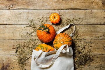 Pumpkins in a bag for shopping on a wooden background. Harvest concept, autumn, Halloween eve....