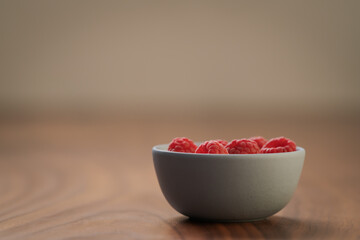 Yogurt with fresh raspberries in blue ceramic bowl on walnut table