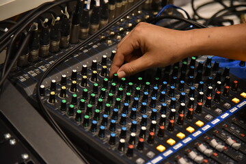 hands on the audio mixing board