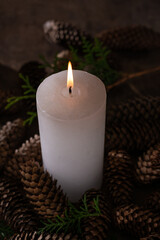 Christmas candle with light and fir cones