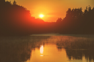 Magical orange sunset over the lake. Serene lake in the evening. Nature landscape