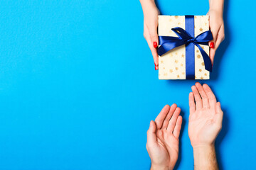 Top view of a gift in male and female hands on colorful background. Congratulation of each other...