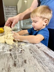 Light skinned child and man kneading dough to make buns / pastry. Parent-child connection concept, home cooking. Free space.