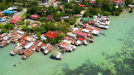 Fototapeta na wymiar Village of fishermen with houses on the water, with fishing boats in Tagbilaran city. Bohol, Philippines.