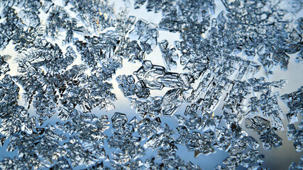 Ice crystals close up on a window glass in winter. Frozen water. Mystical fabulous abstract pattern. Weather forecast: frost, cooling. Blue background or wallpaper. Strong macro