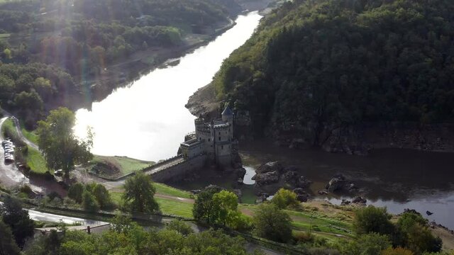 Beautiful Saint-Priest-la-Roche castle in Roanne, France. Aerial view of the historical chateau building ft. sun and lens flare with flying around along the river and nature in HD and 4K