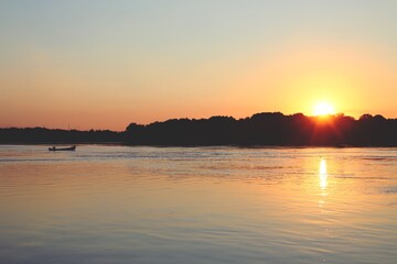 La silueta de un bote navegando por el río Danubio. Delta del Danubio al atardecer a su paso junto...
