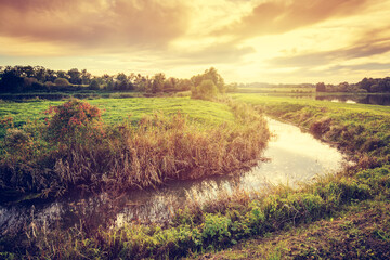 Countryside with small river at sunset.
