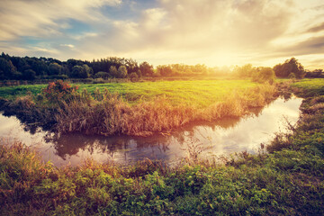 Countryside with small river at sunset.