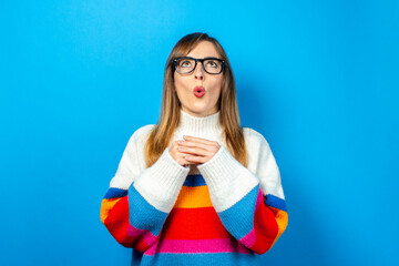young girl in glasses and in a knitted sweater looks up and dreams and thinks, ideas arose on a blue background. Banner