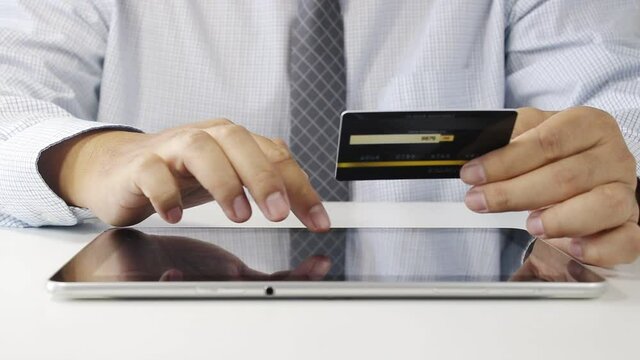 A man sat typing the credit card information on the notebook To apply for the service or perform financial transactions online. Modern business concepts