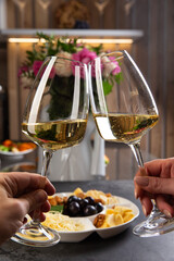 Hands hold two glasses of white wine.