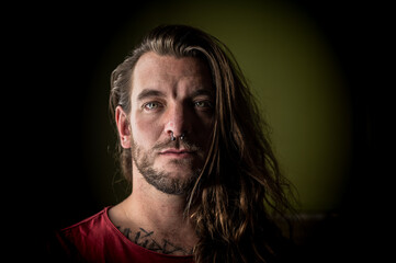 Man with long hair looks seriously at the camera