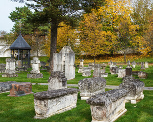 Scenic view of the old cemetery in the time of Golden autumn. Ancient carved gravestones on green grass. Holy Dormition monastery in Staritsa, Tver region, Russia