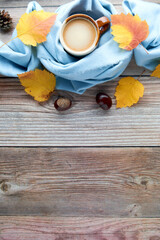 Autumn leaves, cup of coffee and warm scarf on wooden table. Fall season, leisure time, Sunday relaxing, coffee break and still life concept. Selective focus. Top view, copy space.