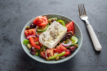 Traditional Greek salad with tomatoes, green peppers, cucumbers, Kalamata olives, capers, red onion and Feta cheese