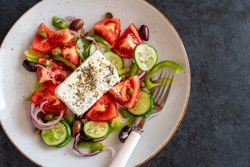 Traditional Greek salad with tomatoes, green peppers, cucumbers, Kalamata olives, capers, red onion and Feta cheese