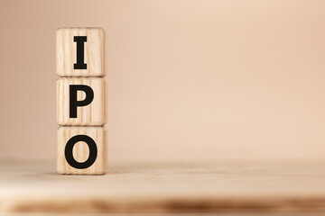 Word IPO Initial public offering on wooden blocks beige background top view, scattered cubes around random letters