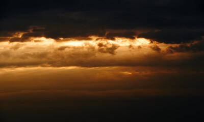 beautiful sunset sky, bright sun and dark silhouette of clouds as a background
