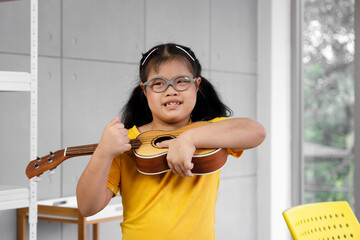 Asian girl with Down's syndrome play ukulele.