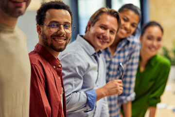 Successful team. Group of young happy multi ethnic business team looking at camera and smiling while standing in the modern office, working together