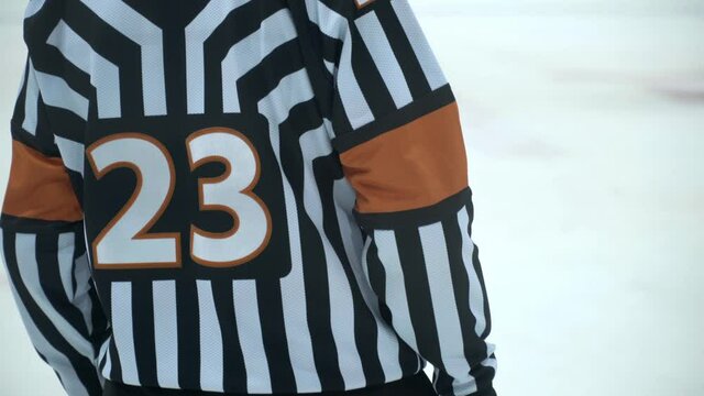 Hockey referee holding a puck in face off position. Front view.