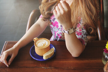 Woman sitting with a cup of coffee on the wooden table. soft focus photo. waiting for someone concept