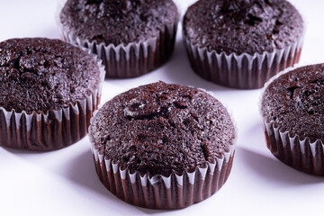 Set of plain dark chocolate cupcakes in paper cups on white background - side View
