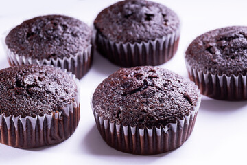 Set of plain dark chocolate cupcakes in paper cups on white background - side View
