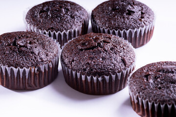 Set of plain dark chocolate cupcakes in paper cups on white background - side View
