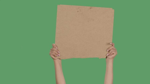 Protest banner copy space. Female hands are holding blank cardboard. Advertising platform. Isolated a green screen, chroma key. Close up. Slow motion.