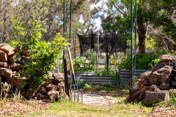 Garden fork resting on metal archway in entrance to cottage vegetable garden 