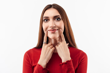 Young beautiful woman pretends to smile, stretches her mouth into a smile. Fake smile concept