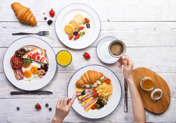 Breakfast is served on a light board. Fried eggs, omelet, croissant, coffee, dessert, place for text.