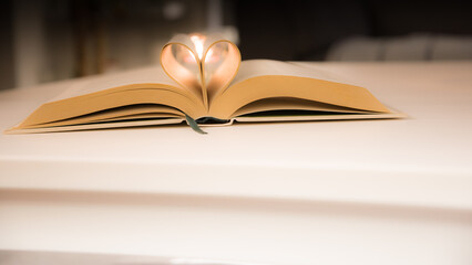 Naklejka premium The old book opens, and the book page rolls into the heart colorful background selective focus and shallow depth of field