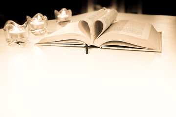Gold wedding rings, heart book, background blur