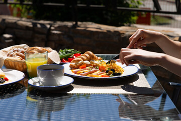 Breakfast outside. Fried eggs, coffee, croissants. Hands in the frame.
