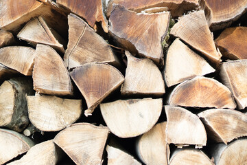 Fototapeta premium Dried firewood stacked under the wall. Background of dry chopped firewood logs in a pile. Close up texture