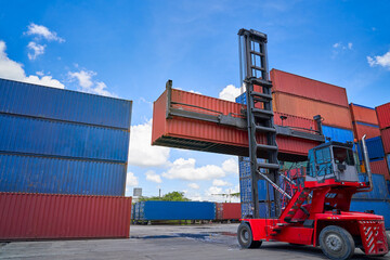 red forklift in cargo site of box container in blue sky background