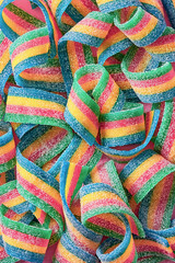Colorful sugar candy ribbon on a pink background viewed from above. Top view. Full frame