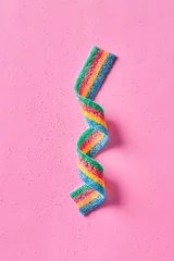 Poster Colorful sugar candy ribbon on a pink background viewed from above. Top view.  © virtustudio